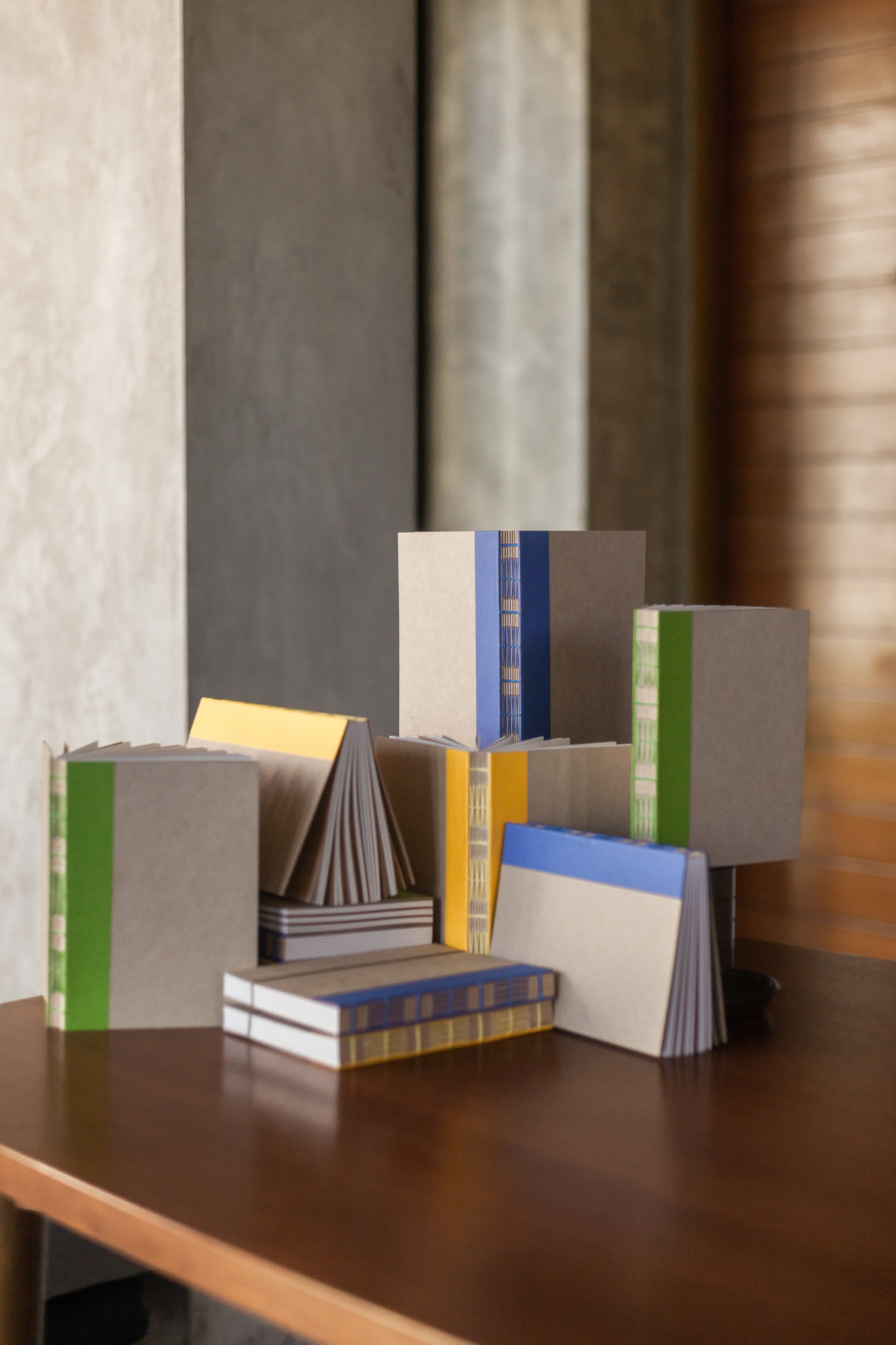 Carnets de la collection LEM, disposés graphiquement, matière kraft et couvertures colorées vert, jaune et bleu